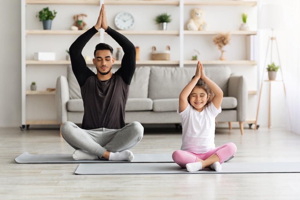 kid doing yoga with father at home