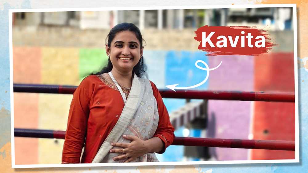 Kavita smiling widely against a rainbow coloured wall.