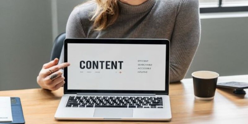 A woman showing content on a laptop screen