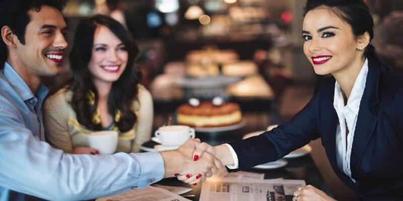 Two women are shaking hands at a restaurant table
