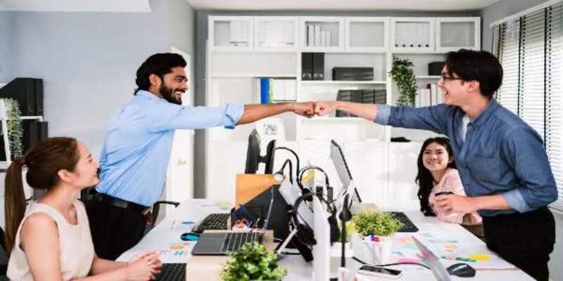 Cheerful businessman partners making fist bump with a smile as teamwork positive