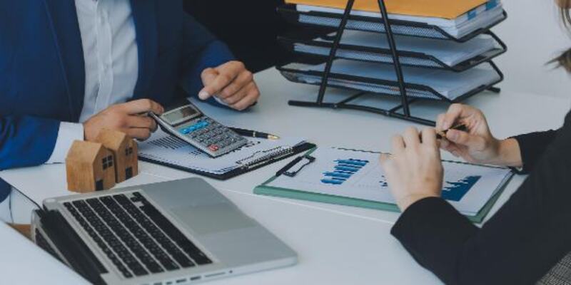 Meeting in 2 business persons and laptop and calculator on table with graphs