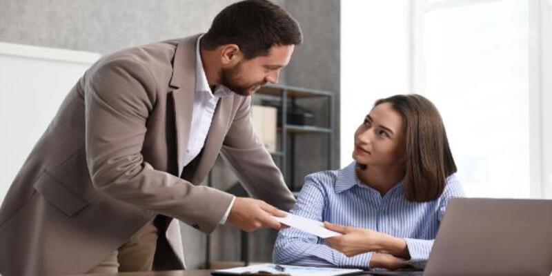 Boss giving salary in paper envelope to employee indoors