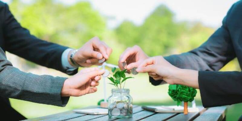 Business people put coin to money saving glass jar gyre