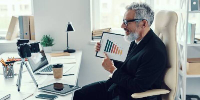 Confident mature man in elegant suit showing chart and sharing business experience