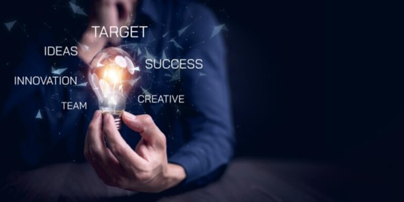 Businessman hand holding light bulb with icons and working on desk creativity and innovation