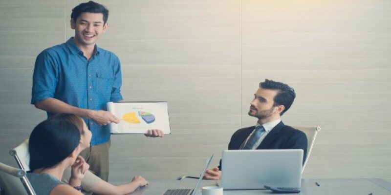 Young man using charts on paper while standing in a meeting