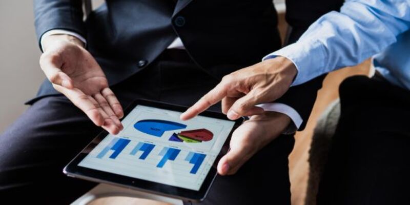 Midsection of man holding mobile phone with charts on screen