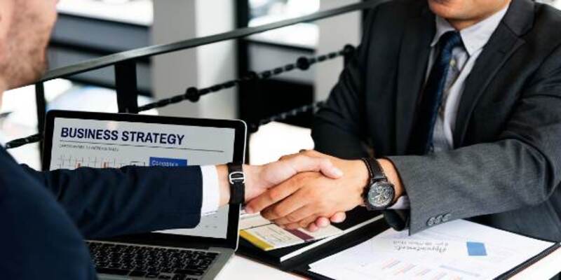Businessmen handshake deal agreement with graphs on table concept