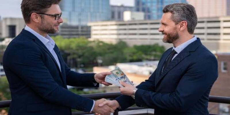 Businessmen shaking hands and receiving banknote businessman giving money outdoor