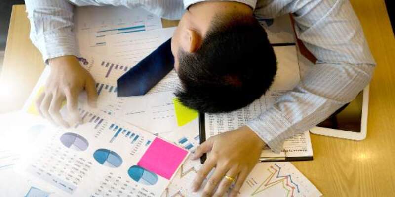 High angle view of businessman exhausted on desk with charts
