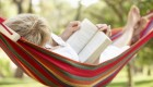 Senior Woman Relaxing In Hammock With Book