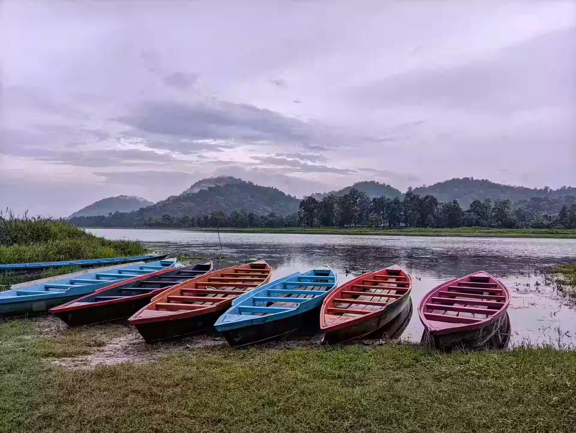 Scenic Lake View in Assam Colorful boats on a lake with hills in Assam