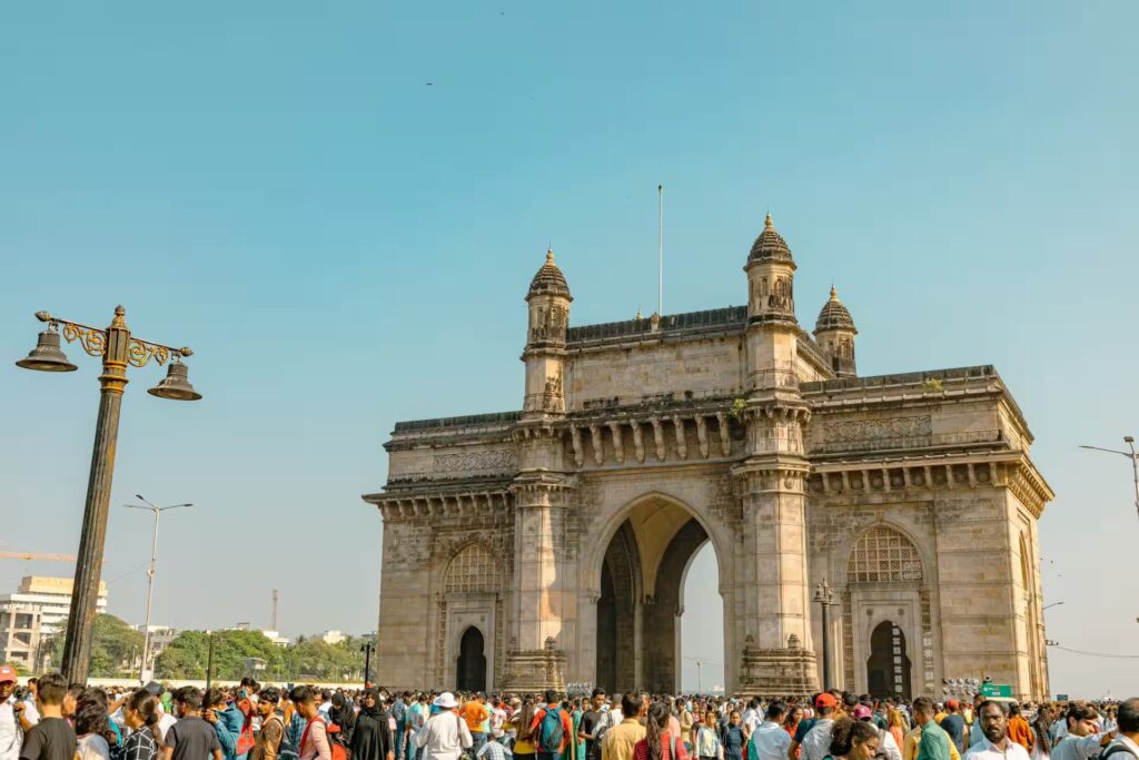 Iconic Gateway of India monument with clear sky and visitors around