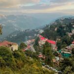 Scenic view of a hillside town with colorful houses and mountains in the background