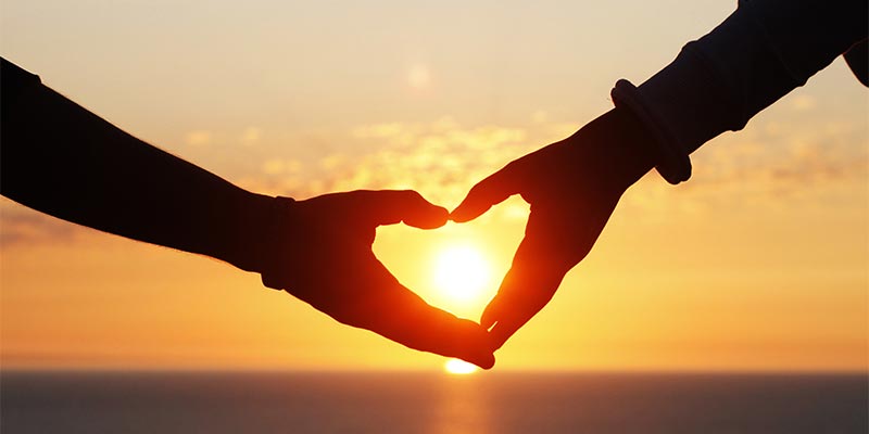 A couple making shape of a heart with their hands