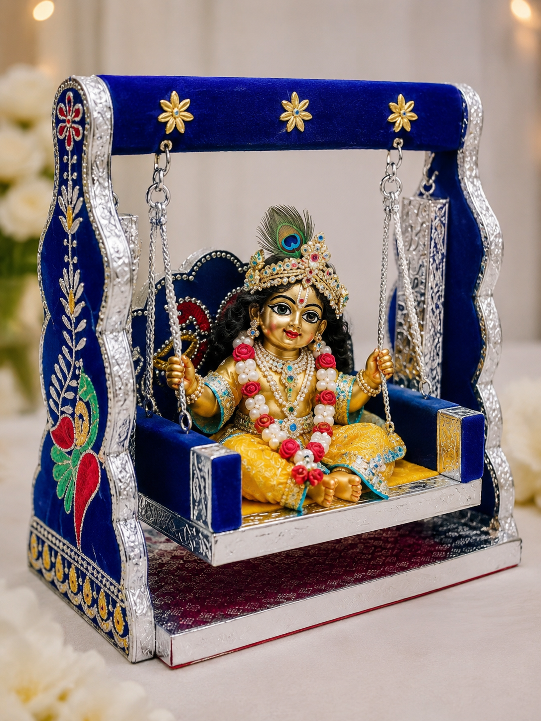 Laddu Gopal wooden jhula swing decorated with blue velvet, silver trim, and colorful floral accents