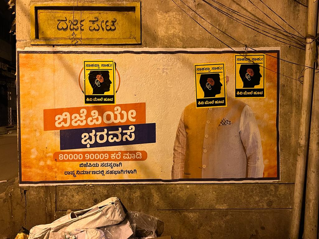 WhatsApp Image 2023-02-18 at 10.32.20 AM (1) Posters of #Kivimelehoova stuck on BJP's achievement stickers overnight in Bengaluru