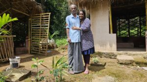 Annie and her father, in front of two huts they've fashioned from mud and bamboo.