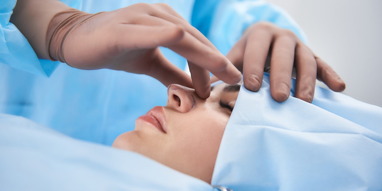 Surgeon in rubber gloves making rhinoplasty for woman. (iStock)