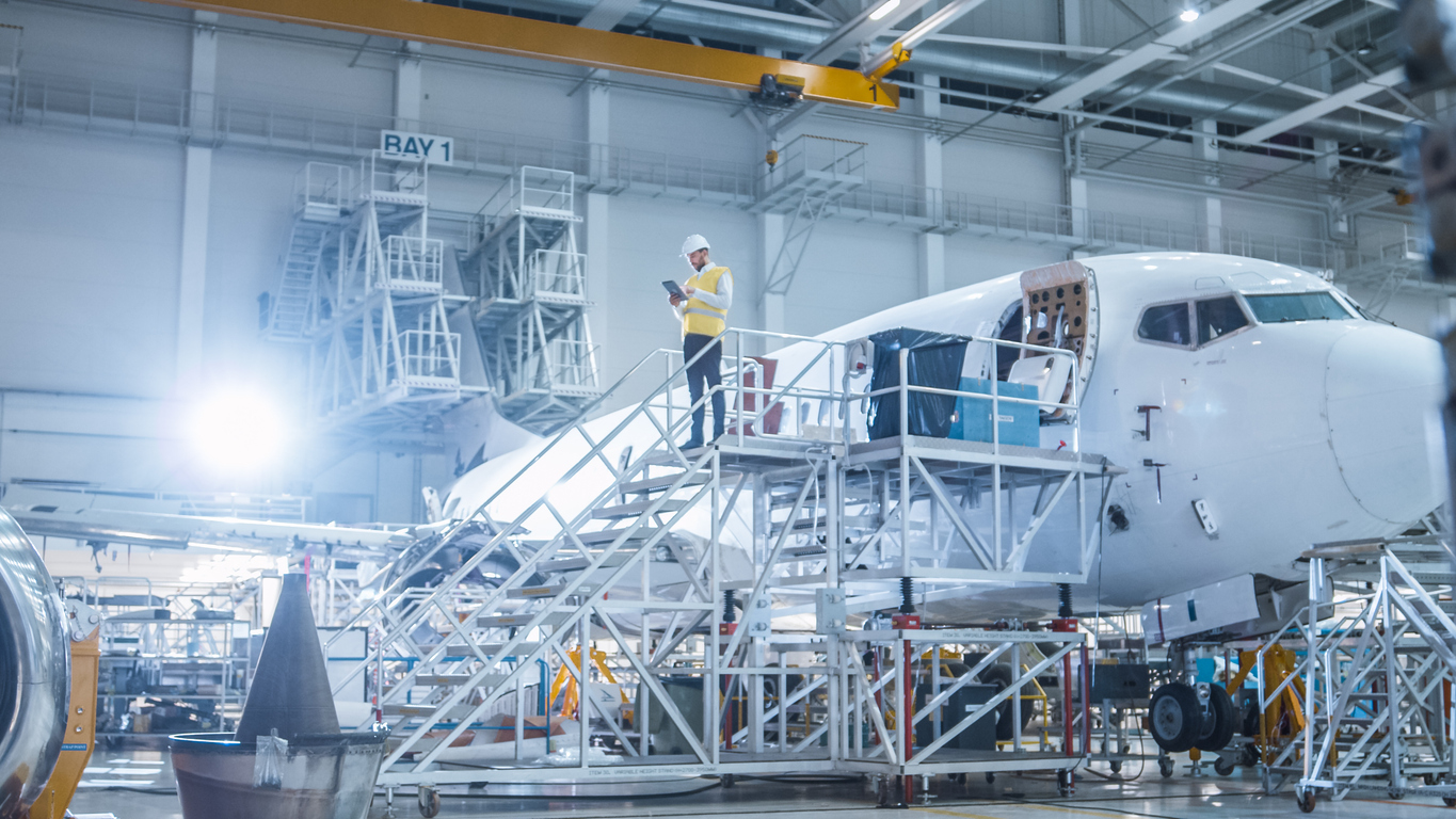 Engineer in Safety Vest Standing next to Airplane in Hangar aircraft maintenance licence suspension