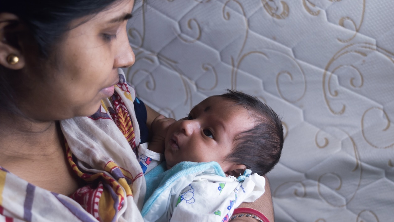 Close up face of a cute newborn baby boy happily looks at his mother in her mother lap. One month old Sweet little infant toddler. Indian ethnicity. Front view. Happy mother’s day background image. Why did Telangana record the third-worst sex ratio at birth in 2022?