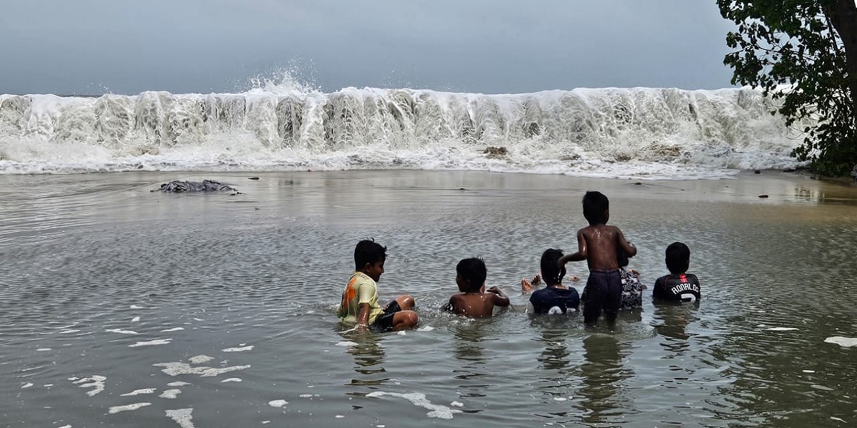 Children in Chellanam play in the sea's floodwaters while their homes stay under water.
