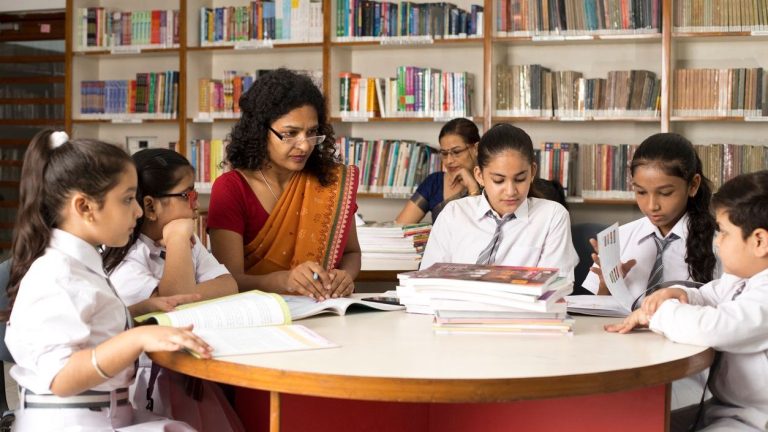 A teacher teaching students in library at school.(iStock)