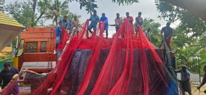 Fisherfolk in Chellanam carrying nets for repair.