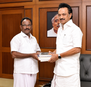 M.K. Stalin and writer Imayam stand together in an office while holding a stack of books, with a framed portrait visible in the background.