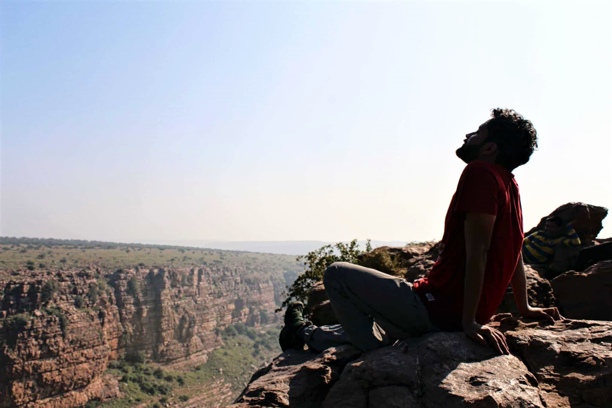 man sitting at the edge of bedrock feelin the nature at mountain