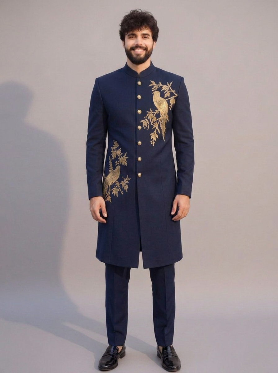 Elegant full-length navy blue Bandhgala suit featuring intricate antique gold bird and foliage embroidery on the chest and lower front panel. The outfit includes a structured mandarin collar, metallic front buttons, matching tailored navy trousers, and black leather formal shoes. Styled with a modern slim fit, this luxury ethnic ensemble is ideal for weddings, receptions, engagements, cocktail parties, and festive celebrations.