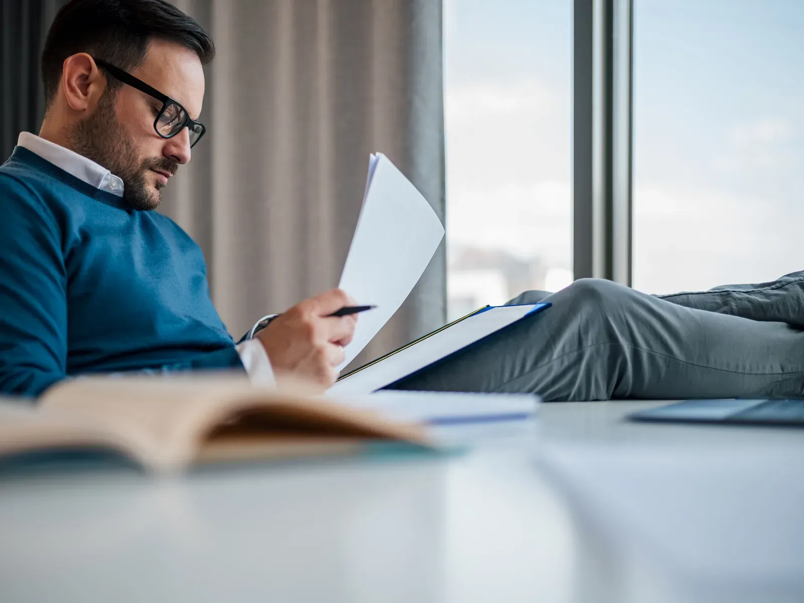 Professional reading analysis documents at a desk by the window