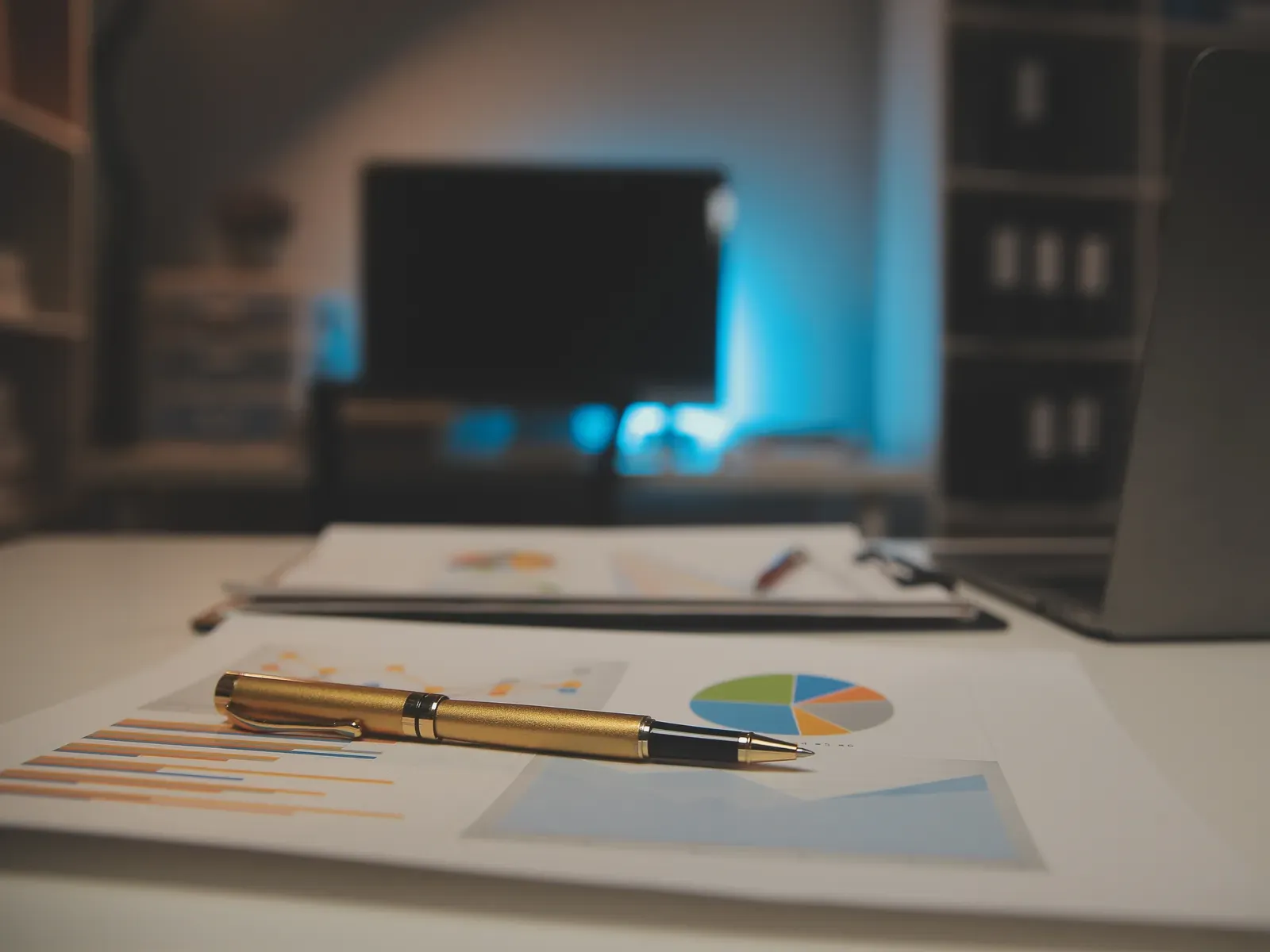 Laptop + printed charts on a dark desk