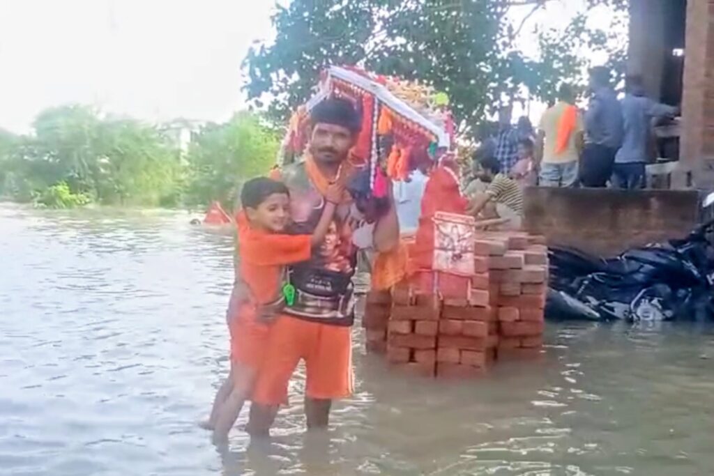 सई नदी में आई बाढ़ के गहरे पानी के बीच से होकर हर हर बम बम का नारा लगाते हुए जलाभिषेक करने पहुंचे सैकड़ों कांवरिया