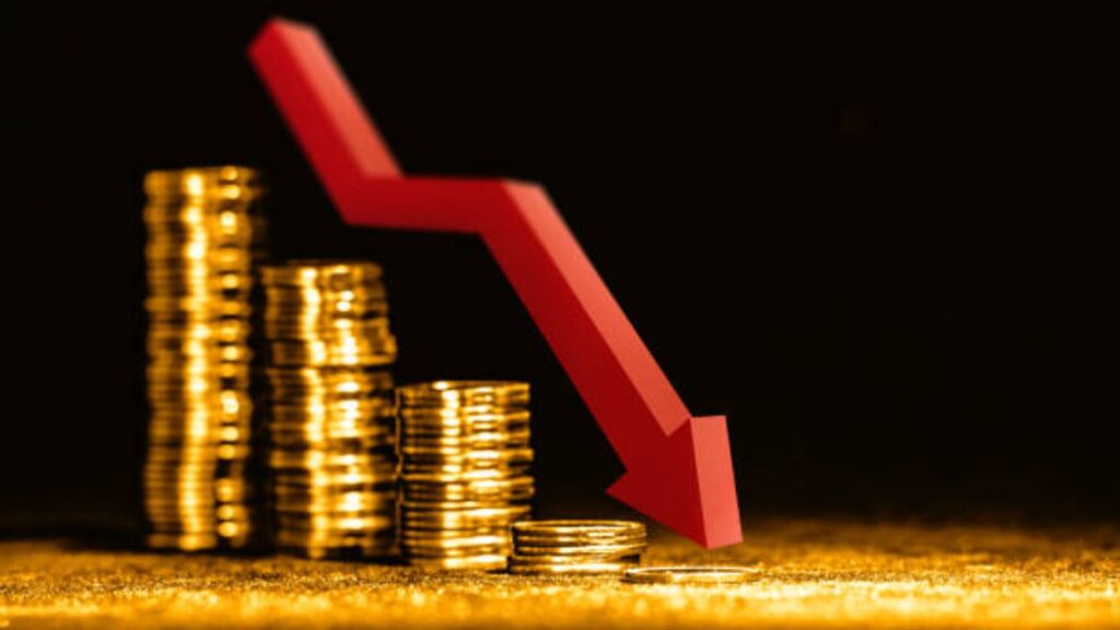 Gold coins and bars with red downward trend arrow showing price fall