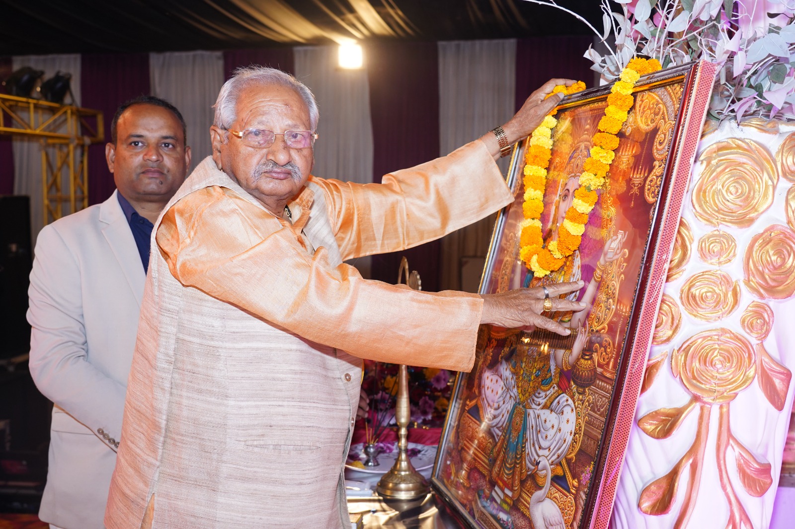 Dr. Balram Bhatt garlanding the portrait of Goddess Saraswati.