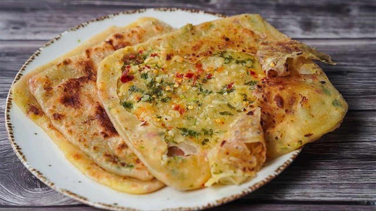तैयार आटे से लोई बनाकर उसे गोल बेल लिया जाता है। बेली हुई रोटी पर सबसे पहले गार्लिक बटर लगाया जाता है ताकि पराठे में खुशबू और स्वाद अच्छे से समा जाए। इसके बाद बीच में तैयार चीज और मिर्च की स्टफिंग रखी जाती है। रोटी को चारों तरफ से उठाकर पोटली की तरह बंद कर दिया जाता है और फिर हल्के हाथों से दोबारा बेल लिया जाता है। इस प्रक्रिया में ध्यान रखना जरूरी है कि स्टफिंग बाहर न निकले, जिससे पराठा सही तरीके से पक सके और उसका स्वाद बरकरार रहे।(फोटो सोर्स- Pinterest)