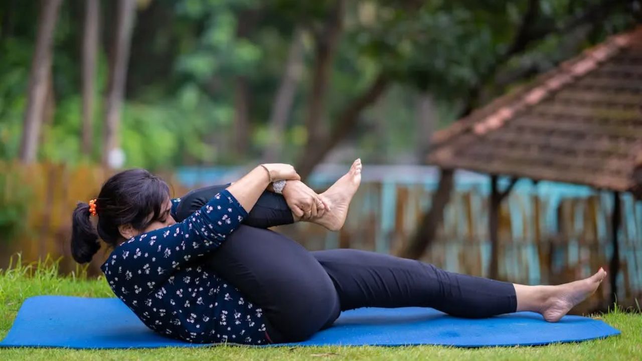 पवनमुक्तासन में पीठ के बल लेटकर एक या दोनों घुटनों को धीरे-धीरे पेट की ओर लाया जाता है। इस दौरान सांस सामान्य रखें और शरीर पर जरूरत से ज्यादा दबाव न डालें। योग में इस आसन को गैस से जुड़ी असहजता के लिए उपयोगी माना जाता है, हालांकि इसके प्रभाव के वैज्ञानिक प्रमाण सीमित हैं। कमर या पेट में दर्द होने पर इसे करने से बचें। किसी परेशानी में दर्द बढ़े तो अभ्यास रोक दें। (Img- Pinterest)