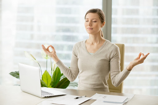Female employee meditating at her office desk for employee wellness