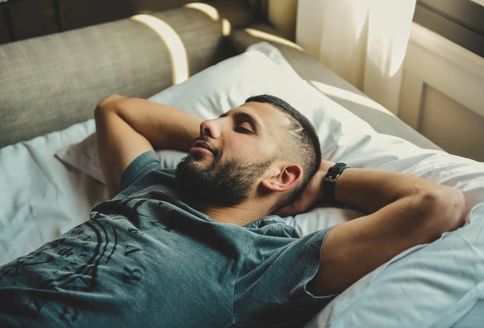 Man rests on a bed near a window
